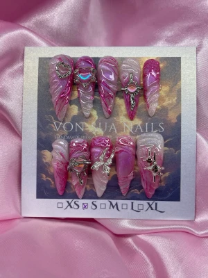 PinkVenom (S);Long Stiletto - Unika handgjorda press-on naglar i rosa och lila toner med swirlmönster och 3D-effekt. Dekorerade med silvriga smycken som hjärta, fjäril och stjärna. Långa, spetsiga och riktigt statement! Perfekt för dig som vill sticka ut med coola detaljer.S: 15 mm, 11,5 mm, 12 mm, 11 mm, 9 mm 