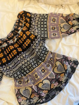 Mönstrad blus  - Säljer en färgglad blus med unikt mönster. Blusen har bred resår vid axlarna och trekvartsärm. Materialet är tunt och luftigt, perfekt för en trendig och avslappnad stil. Skriv vid frågor och pris kan diskuteras!💕💕