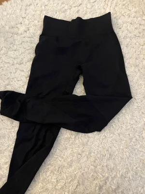 Svarta seamless leggings 157 - Säljer ett par svarta seamless leggings från 157 med hög midja och ribbade detaljer. De är stretchiga och sitter tight, perfekta för träning eller chill. Materialet är mjukt och följsamt för maximal komfort.
