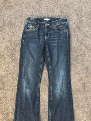 Blå bootcut jeans med kontrastsömmar - Bootcut jeans från Ginatricot storlek 170. Går att spänna i midjan 
