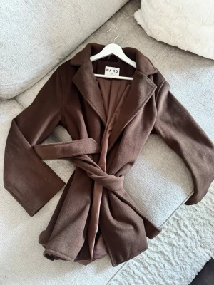 Brun kappa  - Brun vårkappa, är ett material som inte ska noppra, väldigt ”lent” material och inte fleece (svårt att förklara😅) så hår ska inte fastna på kappan lika mycket heller. Storlek 34 men passar mig som är 36/38. Använd 1 gång. Perfekt till vår och höst