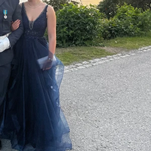 Mörkblå balklänning - Säljer nu min marinblåa balklänning då jag endast haft användning av den en gång! Väldigt vacker och elegant balklänning som sitter fint med fluffig tyllkjol. Den har vackra blommiga detaljer och strassdetaljer runt hela bysten inklusive backlinje och i ryggen. Jag har endast använt den vid ett tillfälle där jag mestadels satt ner så den är i nyskick! Märket är Mascara och jag köpte den för 2.831kr i somras. (Ps, säljer matchande handskar!). Hoppas nu att någon annan kan få användning för den!💙