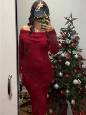 Röd ribbad offshoulder stickad klänning - Säljer en röd stickad klänning med ribbad struktur och bred offshoulder-krage. Klänningen har lång ärm och figurnära passform, perfekt för dig som vill ha en mysig men snygg look. Passar till vinterns alla tillfällen.