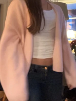 Ljusrosa fluffig kofta - Mysig ljusrosa kofta med oversized passform och långa ärmar. Koftan är fluffig och har en öppen front utan knappar, perfekt att slänga över en topp. Passar dig som gillar en avslappnad och trendig look.