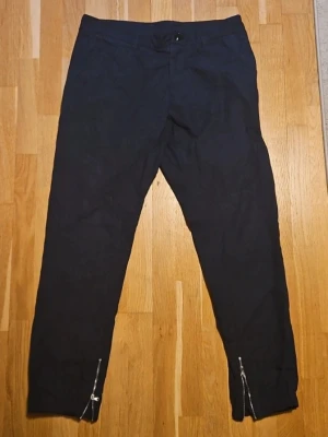 Mauro Grifoni byxa - Blå byxor i smal passform med dragkedjor vid bensluten. Snygg minimalistisk look som passar till det mesta. Tillverkade i ett mjukt bomullsmaterial för skön känsla hela dagen.