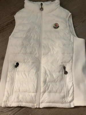 Ny vit väst - Snygg vit dunväst med hög krage och dragkedja framtill. Mukt material som håller värmen. Perfekt för lager på lager och streetwear.