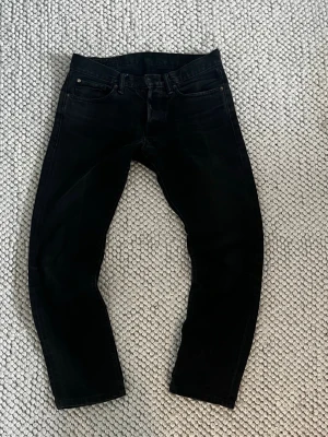 Svarta slim fit jeans - Snygga svarta slim fit jeans med klassisk femficksdesign och dragkedjegylf. Jeansen har en diskret tvättad look och raka ben. Perfekta för dig som gillar en stilren och enkel look. Materialet är mjukt och stretchigt för extra komfort.