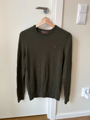 Mörkgrön stickad tröja Morris - Mörkgrön stickad tröja från Oscar Jacobson med rund halsringning och diskret logga broderad på bröstet. Mindre i storleken.