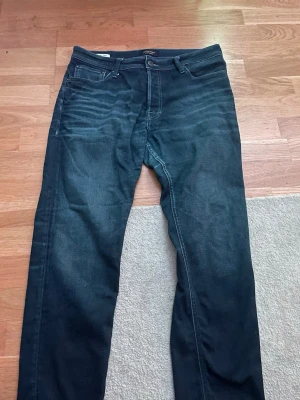 Mörkblå Jeans - Snygga mörkblå slim fit jeans med klassisk femficksdesign och subtila slitningar framtill. Jeansen har normal midja och raka ben. Perfekta till en avslappnad streetwear-look.