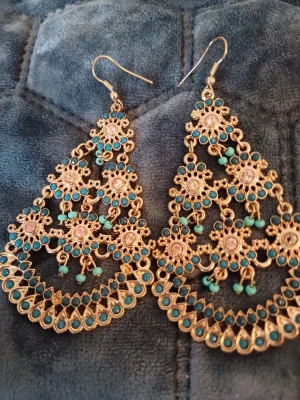 Tre olika örhängen  - Unika, stora örhängen i guldton med massor av små blå pärlor. Triangelformade och dekorerade med blommönster och hängande detaljer. Perfekta för dig som vill sticka ut, ett par gul runda örhängen, hjäte fina örhängen med guld och 3 vita pälor. Priset är mellan 90-180 kr skriv vilka örhängen ❤️