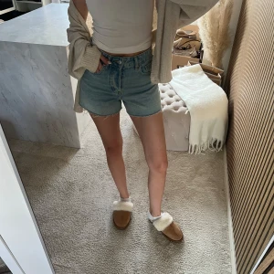 Blå denimshorts från h&m - Snygga blå denimshorts från hm med klassisk femficksdesign och råa benslut. Shortsen har en midwaist passform och är perfekta för varma dagar. Styla med en enkel topp eller hoodie för en chill look.