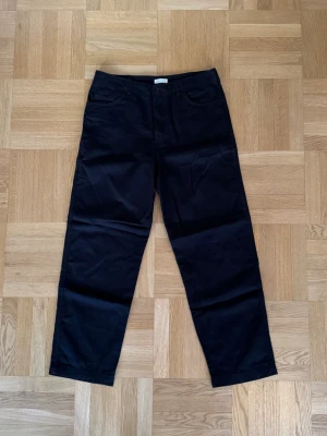 Svarta raka chinos från Arket - Ett par svarta raka chinos från arket i storlek 48. Mått: midja - 42cm, innerben - 71cm, fotöppning - 21cm.
