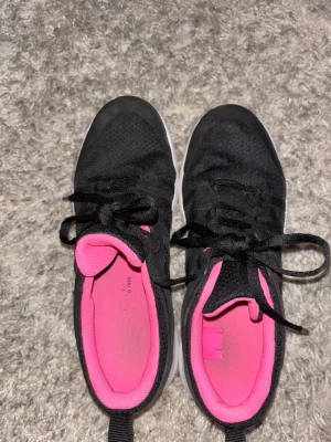 Svarta skor  från soc med rosa foder - Snygga svarta soc skor med rosa innersula och foder. Skorna har klassisk låg profil, snörning och vit sula. Perfekta för dig som vill ha en sportig och färgglad touch på din outfit. Materialet är textil och syntet.