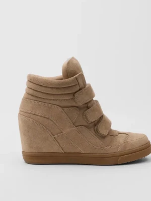 Beige kilklackade stövletter i mocka - Snygga beige stövletter med kilklack och tre breda kardborreband. Skorna är gjorda i mocka och har en sportig, trendig look med vadderad kant och gummisula. Användt fåtal gånger säljer för att jag vill byta färg på dom. Köparen står för frakt.