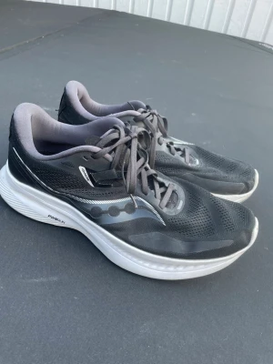 Svarta Saucony Guide löparskor  - Säljer ett par svarta löparskor från Saucony Guide med grå detaljer och vit PHWRUN-sula. Skorna har ventilerande mesh-ovandel, klassisk snörning och reflekterande logga på sidan. Perfekta för dig som gillar att springa eller träna. Storlek UK 10 (eur 45)