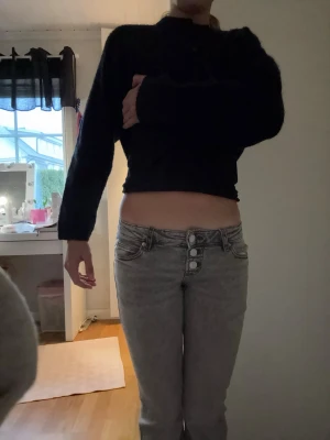 Ljusgråa high waist jeans med knappar - Säljer ett par ljusgråa high waist jeans med tre synliga knappar framtill. Jeansen har smal passform och klassiska fickor både fram och bak. Perfekta för dig som gillar en enkel men snygg stil.