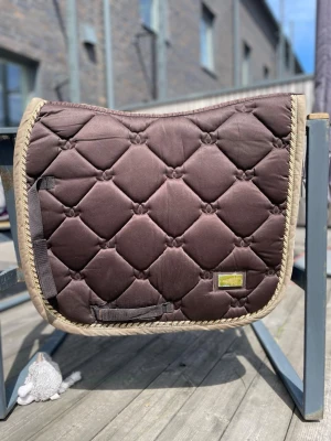 Brun schabrak från Equestrian Stockholm - Säljer ett brunt schabrak från Equestrian Stockholm med quiltat mönster och beige kantband. Kolla in mina andra annonser!🥰 går att pruta