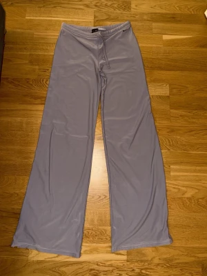 Ljuslila mjukisbyxor från Nike - Säljer ett par ljuslila mjukisbyxor från Nike med Dri-FIT-material. Byxorna har raka, vida ben och dragsko i midjan för skön passform. Perfekta för chill eller träning, riktigt mjuka och lätta att röra sig i.