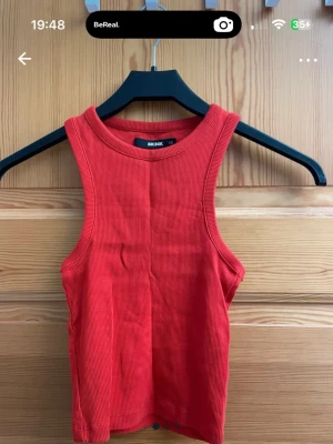 Ribbad linnetopp från Bik Bok - 3 ribbade linnetoppar från Bik Bok. Modellen är ärmlös med rund halsringning och croppad passform, perfekt för en trendig och avslappnad look. Materialet är mjukt och stretchigt för extra komfort. Den röda o vita e lite längre o den svarta e mer croppad🖤 1 för 30kr eller 3 för 60kr