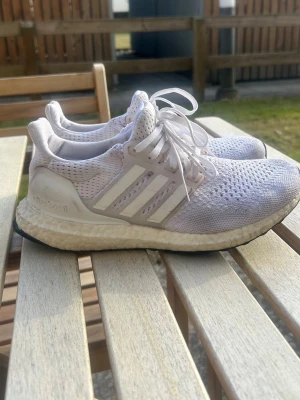Vita Adidas Ultraboost sneakers - Säljer ett par vita Adidas Ultraboost sneakers med stickad mesh-överdel och Boost-sula. Perfekt för vårpromenaderna☀️