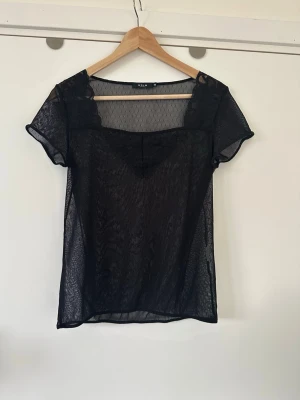 Svart mesh topp från VILA - storlek M - Superfin svart, transparent mesh (spets?) topp / blus från VILA i storlek M. Klassisk modell med korta ärmar och spets-detalj fram. Vackert mönstervävt prickigt halv-transparent tyg. Mycket gott skick, som ny!