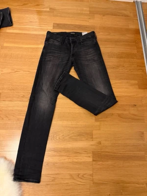 Svarta slim jeans från Jack & Jones - Snygga svarta slim fit jeans från Jack & Jones, modell Glenn. Jeansen har klassisk femficksdesign, diskreta slitningar och är tillverkade i stretchigt denim för en bekväm passform. Perfekta för en stilren och modern look.