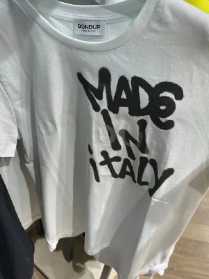 Vit t-shirt från Dondup med tryck - Vit t-shirt från Dondup med svart graffiti-inspirerat tryck på bröstet där det står 'MADE IN ITALY'. Helt ny med tags! Skriv vid frågor eller likannde!