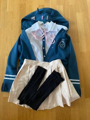 Chiaki nanami cosplay danganronpa  - Kommer med jacka, skjorta, kjol, knästrumpor, rosa band, hårspänne och peruk. Har använt 2-3 gånger och är i bra skick. Strumporna kan vara slitna vid fotsulan men annars i bra skick. Kommer inte med hårnät! Köpt på miccostumes.