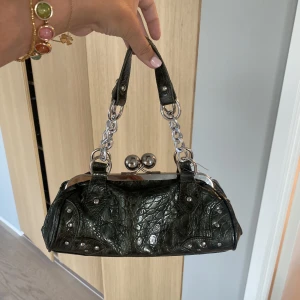 Liten väska - Diskuterbart pris! Väska i ”krokodil mönstrat läder” i mörkt grönt. Sviin cool och tuff, hör av dig vid förfrågan av fler bilden! Väskan är använd men har inga större defekter 💕