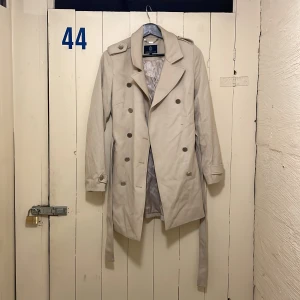 Trenchcoat Stockholm LM - En knapp har lossnat men går lätt att sy på igen! Ord pris 1500
