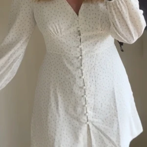 Klänning - Säljer denna vit-blommiga klänning från Nelly. Använd två gånger. Bra skick! 