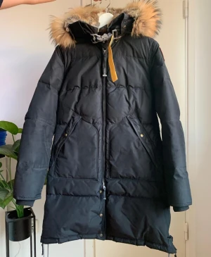Parajumpers Long Bear jacket - Parajumpers Long Bear jacket i svart, storlek M, med tvättbjörnspälskant och mjuk kaninpälsfodrad huva. Jackans yttermaterial består av 100% polyester och innermaterialet av 90% ankdun och 10% ankfjäder.