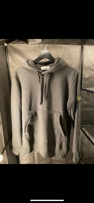 Stone Island hoodie - • Tillverkad i bomull.  • Magficka med dragkedja  • Dragskohuva.  • Avtagbar patch på vänster ärm med den ikoniska logotypen.  PASSFORM    Normal i storleken, vi rekommenderar att du väljer din vanliga storlek