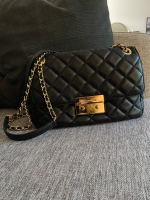 Michael Kors Sloan - Klassisk Michael Kors Sloan handväska med axelrem i mycket fint använt skick. Svart mjukt läder med detaljer i guldmetall. Väskans storlek är perfekt! Den är inköpt på Vestiaire Collective och är sparsamt använd. Dustbag medföljer.