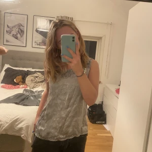 Silver topp - Säljer denna fina silvriga topp. Man kan knyta åt toppen på backsippan så att den sitter mer figursytt, den är i storlek M/L men är mer som S. Toppen  är knappt andvänd och är i fint skick, Pris kan disskuteras💕