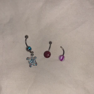 navelpiercings - Säljer tre navelpiercingar, 50:- för den i mitten och längst åt höger och 75:- för den blåa åt vänster. Alla oanvända och gör rent dom innan dom skickas 🫶 Den åt höger saknar en kula