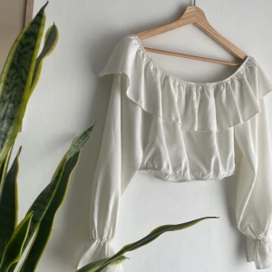 Vit crop top - Säljer denna blusen/crop topp eftersom den inte passar mig längre. Använt den runt 2 ggr och den är i fint skick utan lösa trådar eller fläckar!