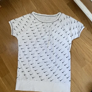Vintage nike t shirt - Vit vintage nike t shirt med små nike märken över hela 