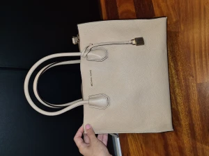 Michael Kors Väska - En Michael Kors axelbandsväska i beige färg. Den är knappt använd så inga slitage eller så. Den har två stora fack och ett mindre fack i i mitten och ett till litet fack inuti det facket.  Dustbag ingår. Bredd: 31 cm Höjd: 24 cm Djup: 13.5 cm