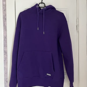 Lila hoodie - En lite tjockare och bekväm hoodie som tom har en en ”mobilficka” i den stora fickan