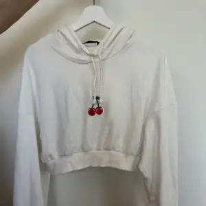 Vit cropped hoodie med körsbärsapplikation.