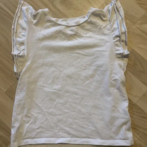 Tröja med volanger - Jätte fin vit t-shirt med volanger. Säljer då den inte passar mig längre.
