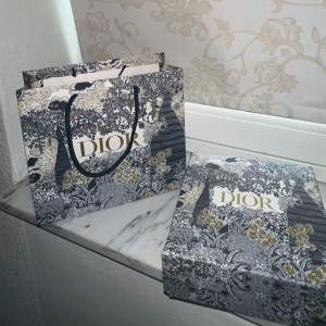 Dior Bälte med svart spänne är en elegant accessoar som levereras i en stilfull Dior-låda och förpackad i en exklusiv Dior-påse. Lådan innehåller en Dior-presentkort som man kan fylla på. Detta bältet är av högsta kvalite och aldrig använts tidigare. 