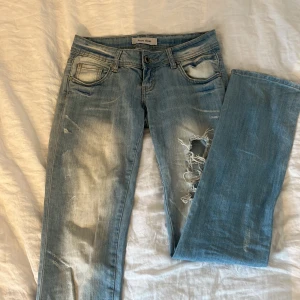 Lågmidjade jeans - Ljusblåa, Lågmidjade jeans med slitningar och urtvättat mönster. Långa o raka ben.