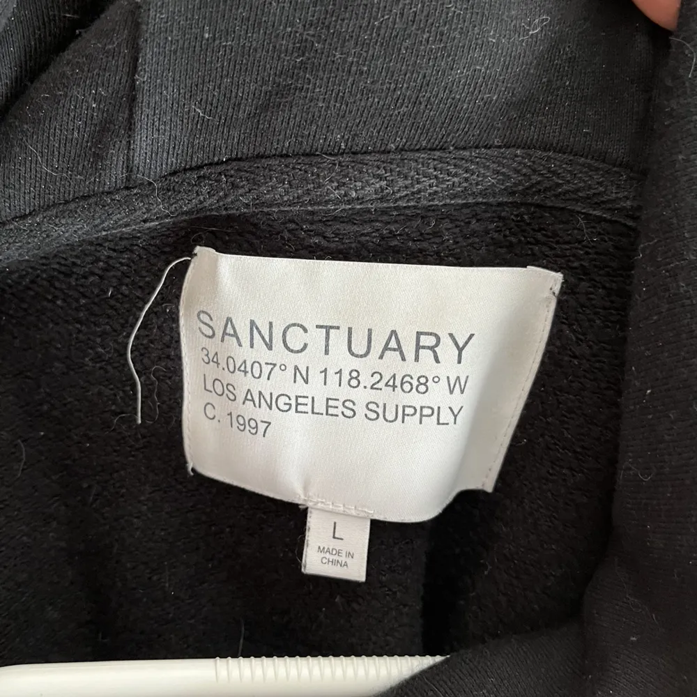 En svart hoodie med tryck fram och text på ryggen. Tröjan är knappt använd och är i gott skick. Köpt i en butik i LA. . Hoodies.