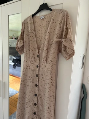 Söt prickig klänning från bubbleroom, strl 42 - Säljer en prickig klänning från Bubbleroom. Knappar fram. Knytning i ärmar och i midjan. Storlek 42.   Nytvättad i parfymfritt tvättmedel  100% polyester