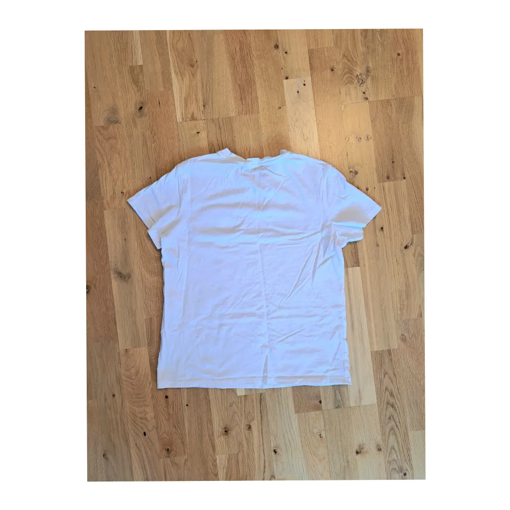 Fin, enkel, vit t-shirt med ett litet regnbågstryck på vänster bröst. Knappt använd. T-shirts.