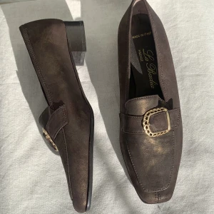 Brun guldiga lågklackade skor! - Jättesnygga bruna skor som reflekterar guldfärg i ljus! Ord. Pris ca 1000kr. (Finns par i strl: 35, 35 1/2, 36) Har fått mycket skor pga familjens nedlagda skobutik!