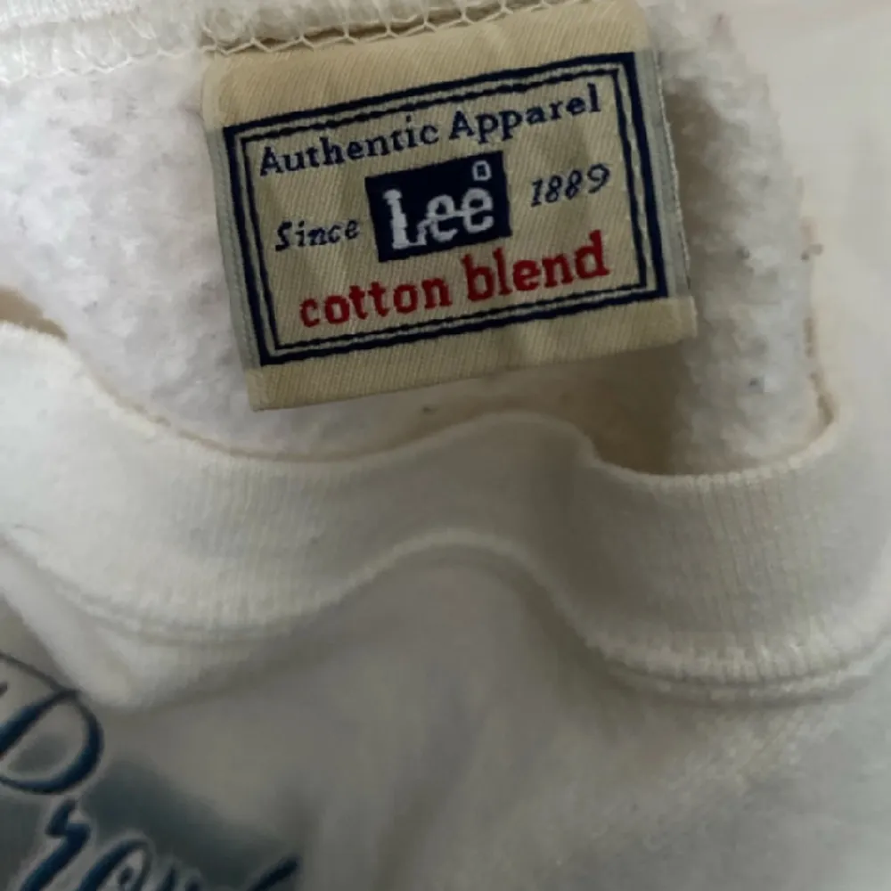 En vit tröja med tryck från Lee, i fint skick. Finns ingen storlek på tröjan men skulle säga XL. Tröjor & Koftor.