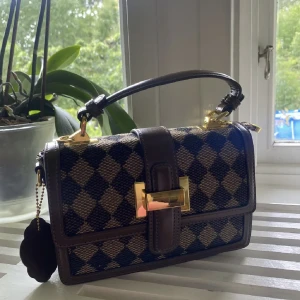 Rutig väska - Söt liten rutig väska. Helt oanvänd med lappen kvar. Den har två axelband, en tunn lång och en bredare och lite kortare. Köpt för 58 amerikanska dollar (ca 640kr) plus frakt (ca 100kr) och tull (strax över 100kr). Säljes för 250kr. Fler bilder kan skickas